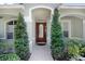 Charming home featuring a beautiful arched entryway, red door, and well-manicured landscaping at 16843 Harrierridge Pl, Lithia, FL 33547