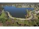 Expansive aerial view of a serene lake surrounded by lush greenery, neighborhood homes, and a winding road at 3217 Partridge Point Trl, Valrico, FL 33596