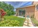 Home exterior, showing a well manicured backyard with healthy green grass, tropical foliage, and large sliding glass door at 3217 Partridge Point Trl, Valrico, FL 33596