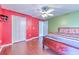 Bright bedroom with red and green walls, hardwood floors, ceiling fan, and closet at 3217 Partridge Point Trl, Valrico, FL 33596