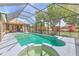 Screened in swimming pool and spa with well manicured tropical foliage and covered outdoor seating area at 3217 Partridge Point Trl, Valrico, FL 33596