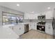 Modern kitchen with stainless steel appliances, white cabinetry, and a large window overlooking the water at 3553 Delta Pl, Holiday, FL 34691