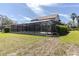 Spacious backyard featuring a screened-in pool and beautiful view of home's exterior at 4404 Lake In The Woods Dr, Spring Hill, FL 34607
