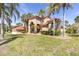Stunning two-story home boasting a lush lawn, mature palms, and a grand entrance portico at 4404 Lake In The Woods Dr, Spring Hill, FL 34607