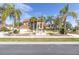 Beautiful home with a red roof and palm trees surrounding a white water fountain, set against a sunny sky at 4404 Lake In The Woods Dr, Spring Hill, FL 34607