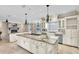 Spacious kitchen featuring a large island with cooktop, marble counters, stainless appliances, and decorative lighting at 4404 Lake In The Woods Dr, Spring Hill, FL 34607
