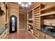 Well-stocked wine cellar featuring wood shelving, tile floor and ornate door at 4404 Lake In The Woods Dr, Spring Hill, FL 34607