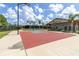 Outdoor basketball court featuring a bright red surface, palm trees, and well-kept landscaping at 7472 Clearmeadow Dr, Spring Hill, FL 34606