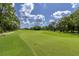 Scenic golf course showcasing lush green fairways, mature trees, and blue skies with fluffy clouds at 7472 Clearmeadow Dr, Spring Hill, FL 34606