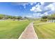 Scenic golf course view with manicured lawns, golf carts, covered seating, and a paved walking path at 7472 Clearmeadow Dr, Spring Hill, FL 34606