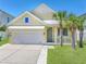 Charming yellow two-story home with a white metal roof, two palm trees, and an attached two-car garage at 7603 S Kissimmee St, Tampa, FL 33616