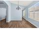 Open dining room with wood floors, arched entryways, elegant light fixture, and natural light at 11009 Silver Dancer Dr, Riverview, FL 33579