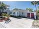 View of the house featuring a long driveway, charming brick accents, and lush surrounding landscaping at 129 94Th Ave, Treasure Island, FL 33706