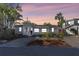 Charming single-story home with manicured yard and exterior lighting at dusk, creating an inviting ambiance at 129 94Th Ave, Treasure Island, FL 33706