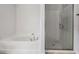 Bright bathroom showcasing a soaking tub and a glass-enclosed shower with tile floors at 14916 Imperial Purple Ln, Wimauma, FL 33598