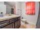 Well-lit bathroom featuring a vanity, toilet, shower, and a colorful coral curtain at 14916 Imperial Purple Ln, Wimauma, FL 33598