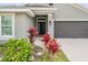 Close up of a home entrance with well kept landscaping, a black front door and gray two car garage door at 14916 Imperial Purple Ln, Wimauma, FL 33598