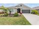 Charming single-story home featuring a well-manicured lawn, gray exterior, and a two-car garage at 14916 Imperial Purple Ln, Wimauma, FL 33598