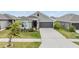 Inviting single-story home showcasing a lush lawn, gray exterior paint, and a two-car garage at 14916 Imperial Purple Ln, Wimauma, FL 33598