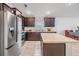 Kitchen features modern stainless steel appliances, dark wood cabinets, and a central island at 14916 Imperial Purple Ln, Wimauma, FL 33598