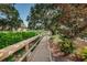Scenic wooden walkway lined with lush greenery and trees, offering tranquil views of the community's serene lake at 1908 Bayshore Ct, Safety Harbor, FL 34695