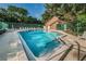 Community pool view on a sunny day includes lounge chairs, fenced perimeter and bath house at 1908 Bayshore Ct, Safety Harbor, FL 34695