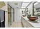Bathroom featuring double bowl sinks, a skylight, and a glass-enclosed shower at 3034 Gull Pl, Clearwater, FL 33762