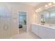 Bathroom featuring double sink vanity, large mirror, and glass-enclosed shower with decorative tile at 34329 Evergreen Hill Ct, Wesley Chapel, FL 33545