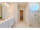 Bathroom featuring a double sink vanity, glass-enclosed shower, and walk-in closet access at 34329 Evergreen Hill Ct, Wesley Chapel, FL 33545
