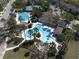 An aerial view of the community pool area, featuring palm trees, lush landscaping, and a clubhouse at 34329 Evergreen Hill Ct, Wesley Chapel, FL 33545