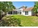Large, grassy backyard showcasing a covered patio and well-maintained landscaping at 441 Village Dr, Tarpon Springs, FL 34689