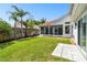 Expansive backyard featuring lush lawn, a private patio, and mature palm trees at 441 Village Dr, Tarpon Springs, FL 34689