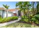 Beautifully landscaped front entrance with a screened porch and tropical foliage at 441 Village Dr, Tarpon Springs, FL 34689
