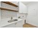 Well-organized laundry room with elegant tile backsplash, quartz countertops, and wooden shelving at 6314 Soratrace St, Lithia, FL 33547