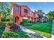 Charming two-story townhome featuring verdant landscaping and vibrant red stucco facade at 6843 Se Dartmouth Hill St, Riverview, FL 33578