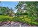 Scenic view of a backyard pond surrounded by green lawn and mature trees at 6843 Se Dartmouth Hill St, Riverview, FL 33578