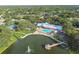 Beautiful aerial view of a community clubhouse with a sparkling pool, lake with fountain, and lush trees at 8130 Braddock Cir # 3, Port Richey, FL 34668