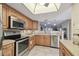 Open kitchen with stainless steel appliances, wood cabinets, and serving hatch to living room at 8130 Braddock Cir # 3, Port Richey, FL 34668