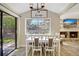 Bright dining area with a white table, modern chandelier, and a view of the backyard and fireplace at 864 Pinewood W Ter, Palm Harbor, FL 34683