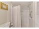 Bright bathroom with a walk-in shower with curtain and grab bars, toilet, and decorative gold-framed mirror at 2507 Royal Pines Cir # 2H, Clearwater, FL 33763