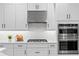 Close up view of white kitchen cabinets, stainless steel range hood and double oven at 2612 Leafwing Ct, Palm Harbor, FL 34683
