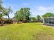 Spacious backyard with green grass, landscaping, and a screened-in porch at 3210 Acacia St, Lutz, FL 33558