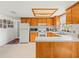 Bright kitchen with wood cabinets, white appliances, and tiled floor creates a clean, functional space at 3210 Acacia St, Lutz, FL 33558