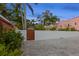 Long paved driveway featuring lush foliage, palm trees and a secured wooden gate at 346 16Th Ne Ave, St Petersburg, FL 33704