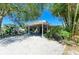 Home exterior featuring a covered carport, tropical landscaping, and gravel yard, enhancing curb appeal at 412 River S Blvd, Nokomis, FL 34275