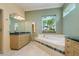 Bathroom featuring an oval bathtub with tile surround, double sink vanity, and a window with a backyard view at 4605 W Vasconia St, Tampa, FL 33629