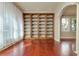 Bright empty room with cherry wood floors and custom wood built-ins featuring a large window with sheer curtains at 4605 W Vasconia St, Tampa, FL 33629