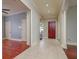 Hallway with travertine floors leading to a red front door and wood floors in another room at 4605 W Vasconia St, Tampa, FL 33629