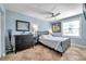 Comfortable bedroom with tile flooring, ceiling fan, blue walls, dresser, side table and a window with natural light at 5101 Coquina Key Se Dr # A, St Petersburg, FL 33705