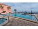 Outdoor swimming pool with hot tub surrounded by lounge chairs and umbrella-covered tables at 5101 Coquina Key Se Dr # A, St Petersburg, FL 33705
